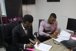 Multi award-winning Gospel artiste, Frank Edwards and Founder/Vice President, Yudala, Prince Nnamdi Ekeh signing the contract documents during the unveiling of Edwards as Yudala brand ambassador.